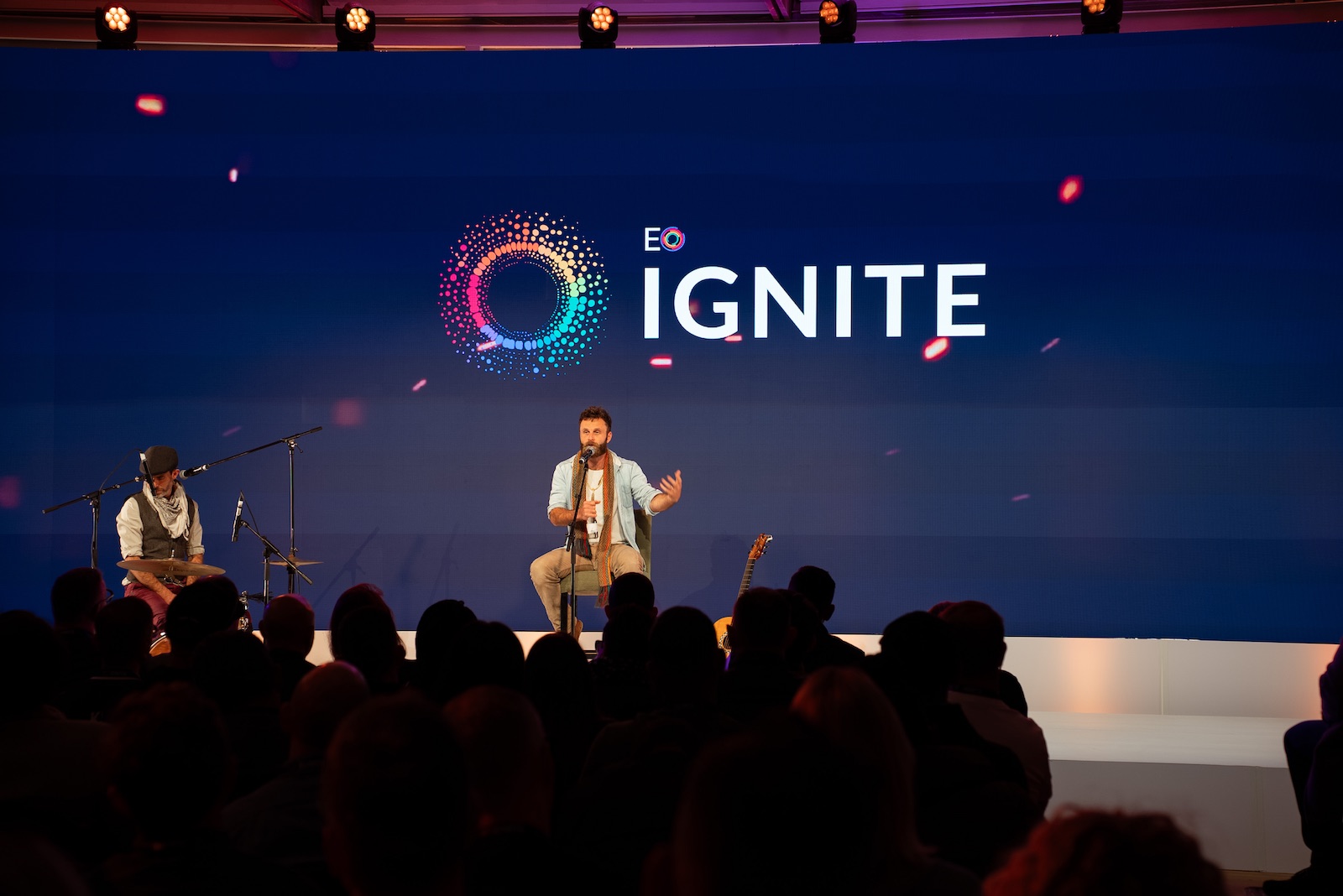 Nathan Maingard seated on stage at EO Ignite, mid-conversation with the crowd, EO Ignite logo lit up behind him